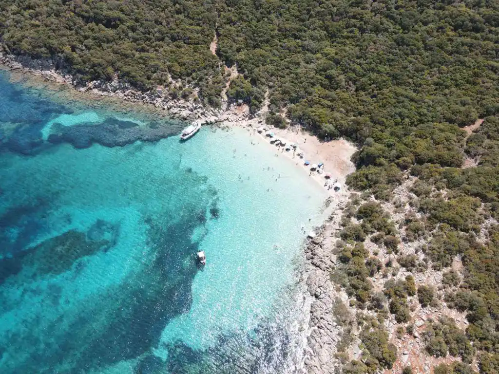 Καταπράσινος ελληνικός κόλπος με γαλαζοπράσινα νερά, τραβηγμένος από ψηλά.